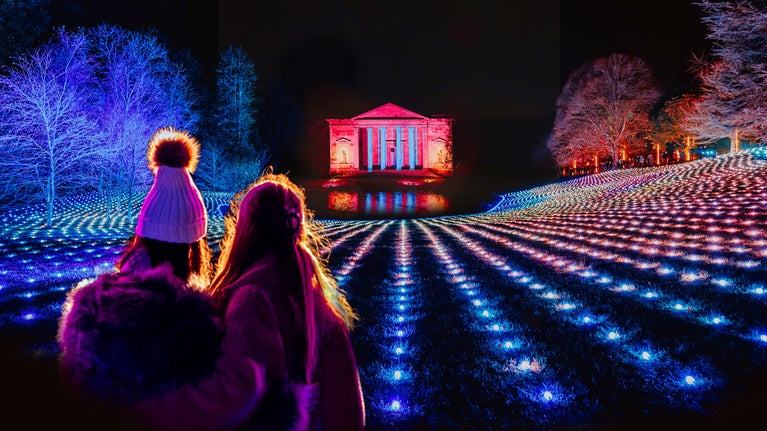 A women and girl looking across the illuminated garden towards the Pantheon